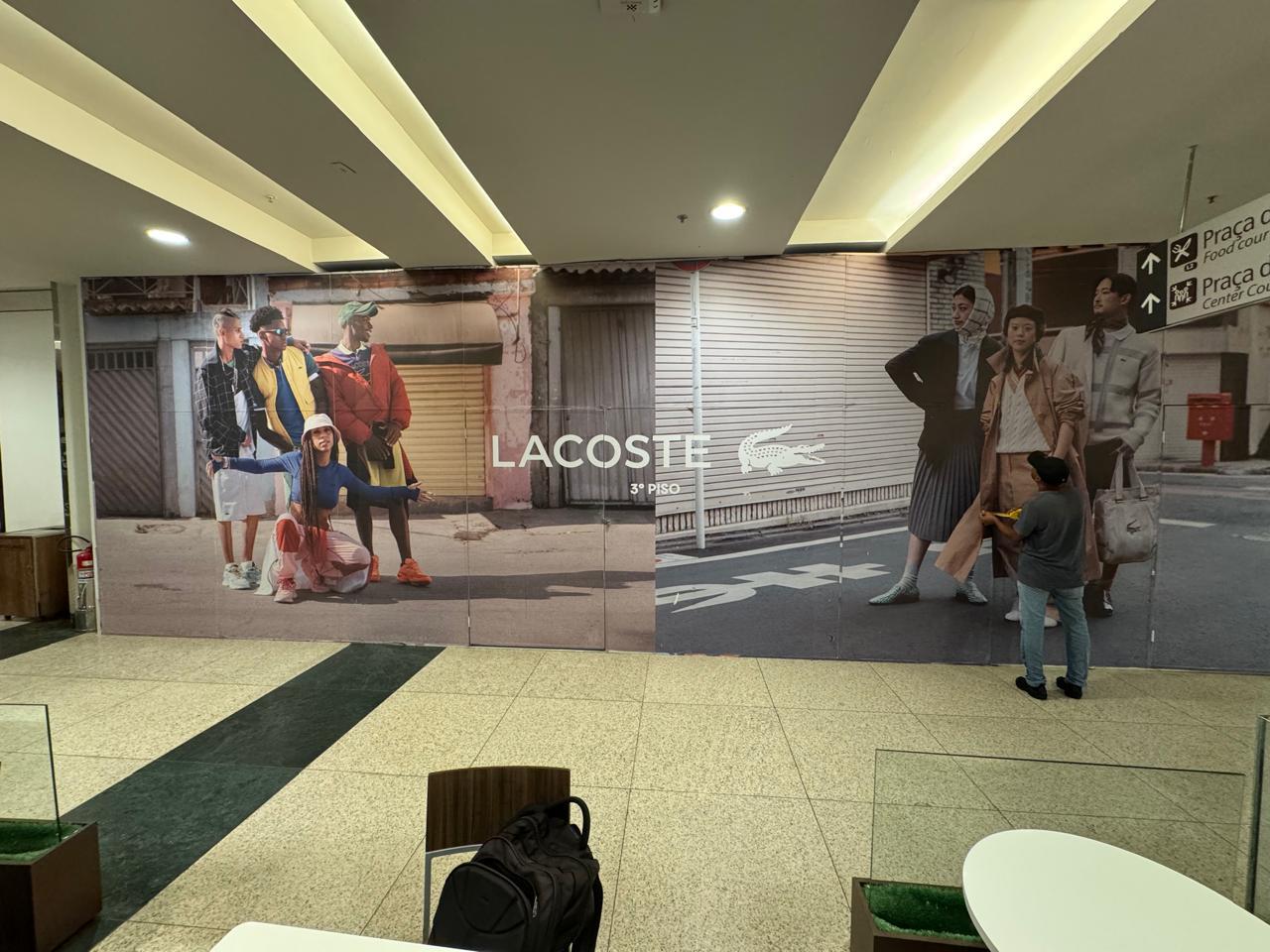 Tapume Lacoste no shopping — adesivação fotográfica de grande formato com campanha de moda streetwear