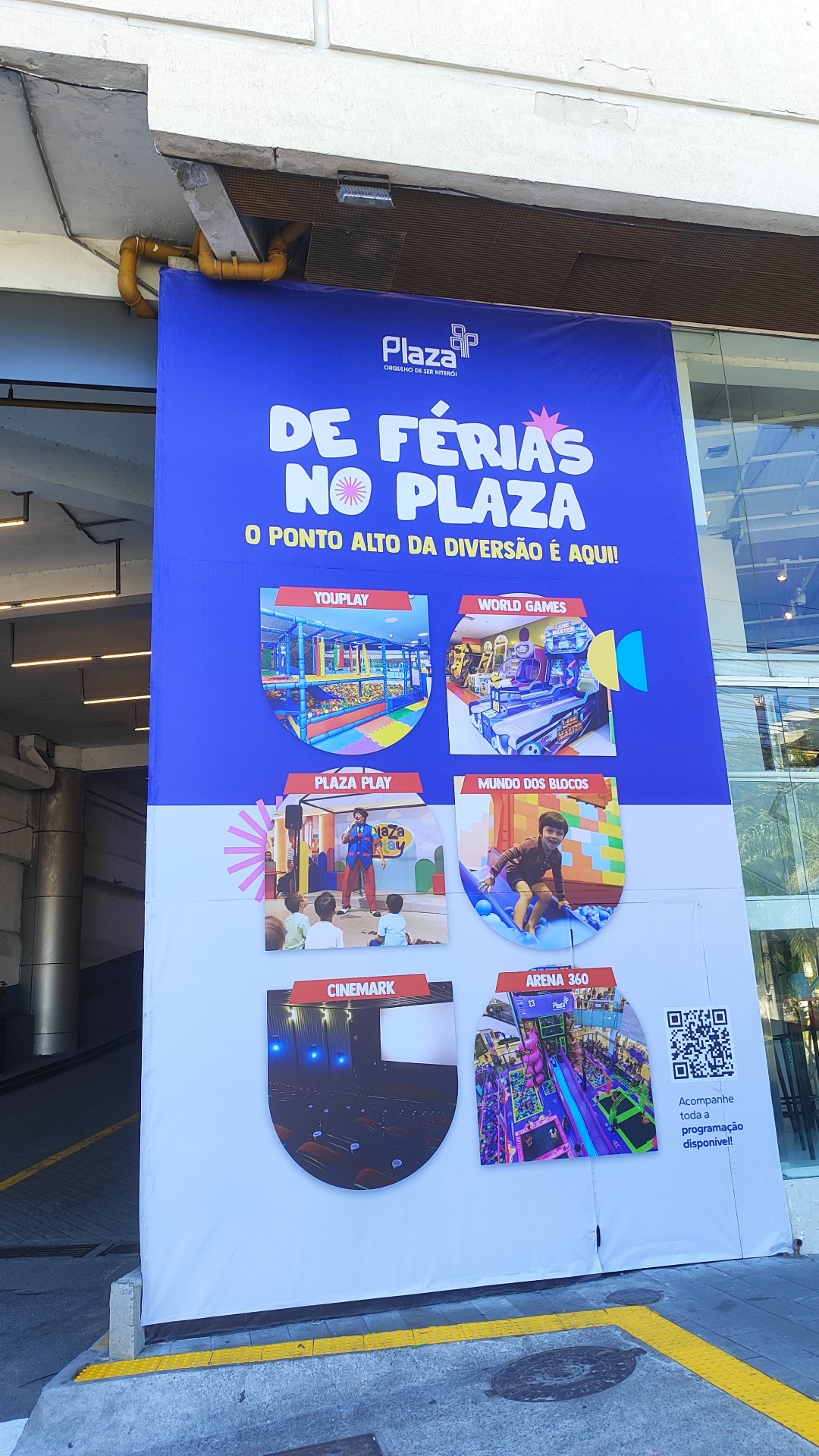 Painel De Férias no Plaza — lona vertical de grande formato em entrada de shopping