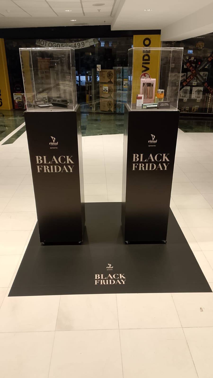 Ativação Black Friday RioSul — totens duplos com vitrines acrílicas e adesivação de piso