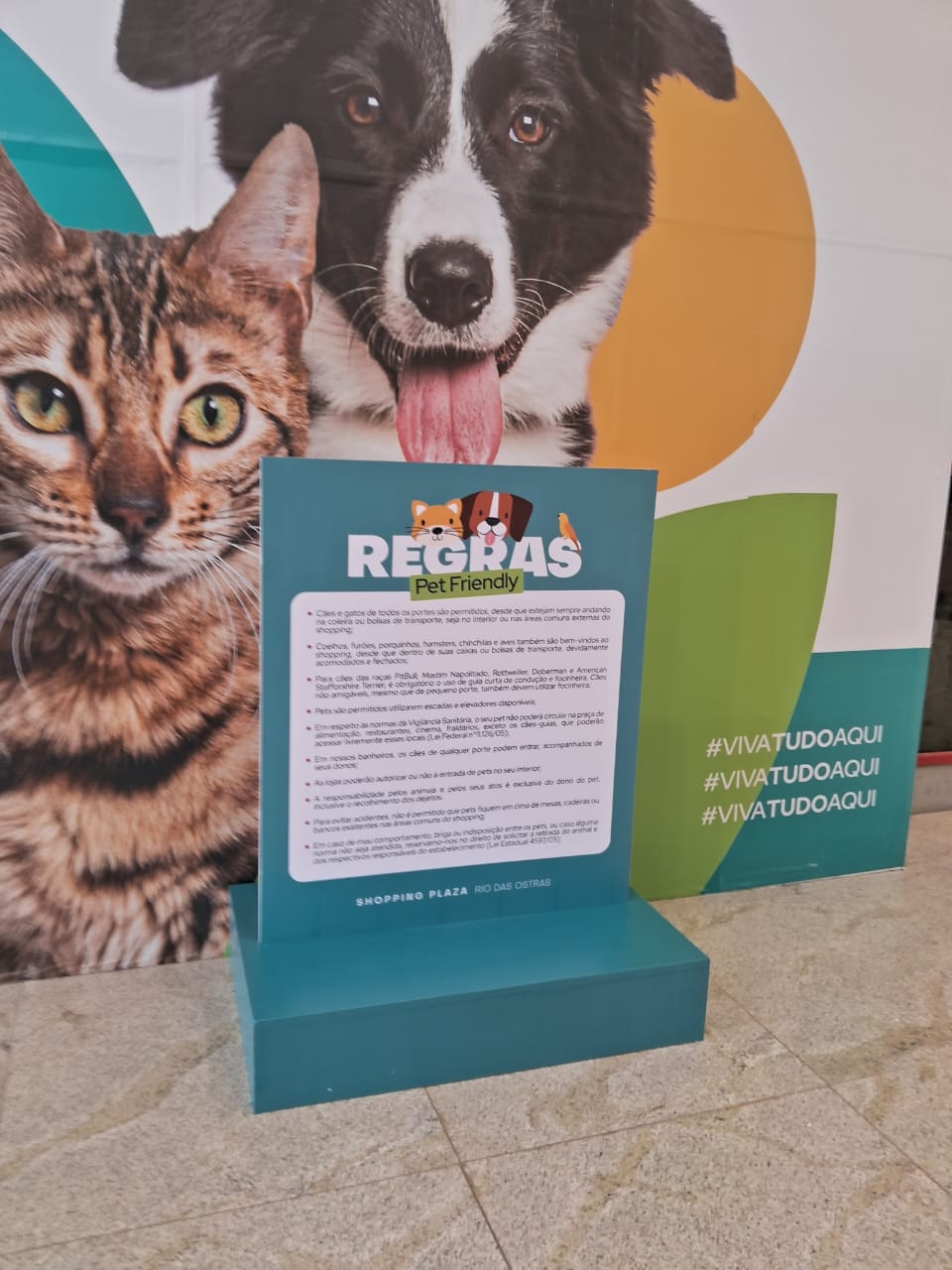 Totem Regras Pet Friendly Shopping Plaza Rio das Ostras — display informativo com painel de fundo de cães e gatos